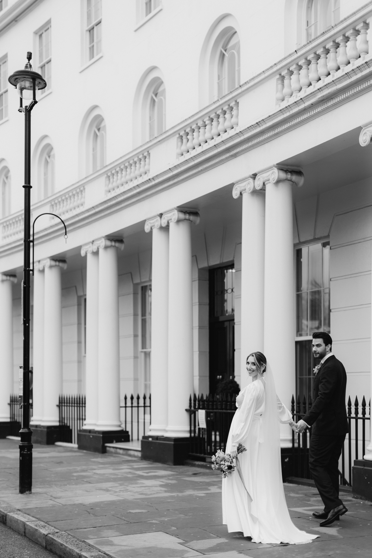 pregnant bride walking on Park Crescent with her groom on their wedding day in Marylebone in London